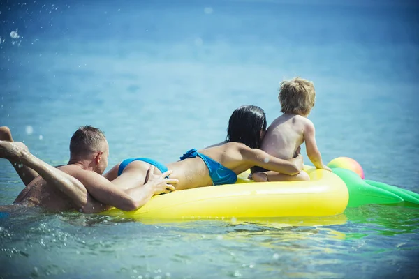 家族での休暇の概念 プッシュ マットレス父泳ぐ 幸せな若い家族過ごす時間を一緒に 楽しい時を過します エアマットレス パイナップル形 海の母と海に座っているかわいい子少年 — ストック写真