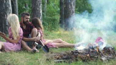 Müzik çalma ve doğada şenlik ateşi zevk mutlu arkadaşlar. Gençler eğleniyor orman. Ormanda oturan arkadaşlar bir kamp ateşi daire.