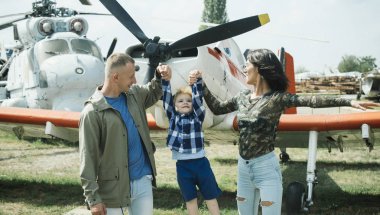 Mutlu aile zaman harcamak birlikte, gezi, helikopter veya uçak arka planda, güneşli bir gün. Anne ve baba ve çocuklarının Havacılık Müzesi havada yürüyüş. Yetiştirme ve geliştirme kavramı.
