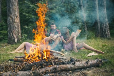 Şenlik ateşi alev kıvılcım ve arka plan üzerinde kişi ile. Kampta yangın yanık. Arkadaşlar kamp ateşi duman içinde rahatla. Kamp, yürüyüş ve turistik. Yaz tatil kavramı.