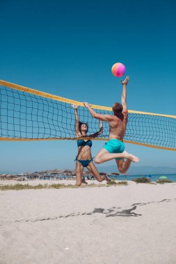 İnsanlar plaj voleybolu oynuyorlar ve sportif yaşam tarzlarıyla eğleniyorlar. Yazın voleybol oynayan bir adam. Kadın ve erkek fitness modeli sağlıklı bir hayat sürüyor sahilde spor yapıyor..