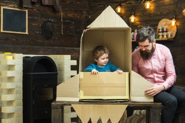 Çocuk mutlu oturmak karton el roket yapımı. Ebeveynlik kavramı. Çocuk Çocuk oyun kozmonot, astronot. Baba, Baba, küçük kozmonot ile Çocuk oyun oturup karton kutudan yapılan roket.