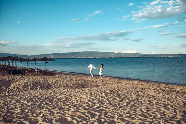男と女は バカンス幸せカップルを保持します 愛のカップルは ビーチ 海岸に立っています 新婚旅行は ちょうど結婚概念 歩いて 楽しみ 海とのスカイラインの背景を持つ愛のカップル — ストック写真