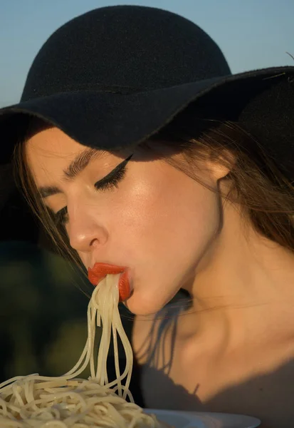 一个漂亮的女人吃黑帽子意大利面的美丽形象 — 图库照片