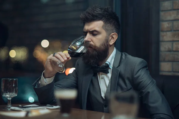 bar customer sit in cafe drinking alcohol. Bearded man rest in restaurant with wine glass. Perfect wine. Date meeting of hipster awaiting in pub. Businessman with long beard drink in cigar club.