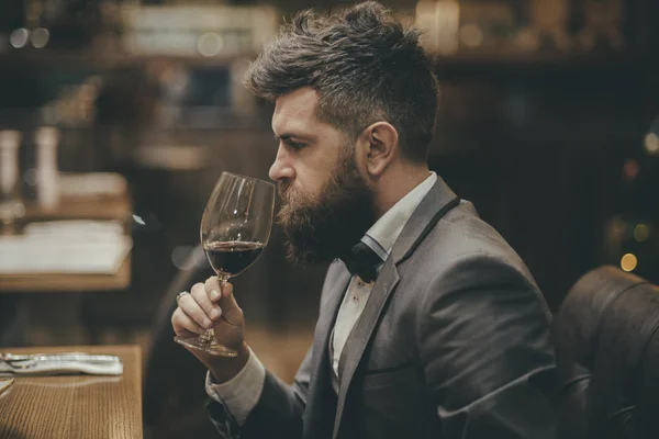 Perfect wine. Businessman with long beard drink in cigar club. bar customer sit in cafe drinking alcohol. Bearded man rest in restaurant with wine glass. Date meeting of hipster awaiting in pub.