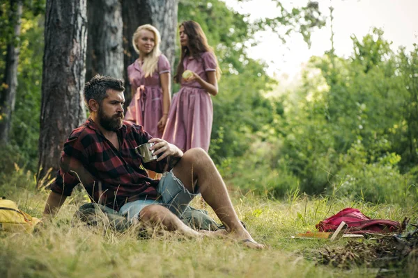 背景をぼかした写真の女性と焚き火でお茶を飲む男ひげを生やした キャンプファイヤーでひげシッと流行に敏感 友人は 森でのキャンプをお楽しみください 夏の休暇の概念 キャンプ ハイキング — ストック写真