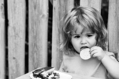 küçük çocuk ahşap çit yakınındaki pasta yemek