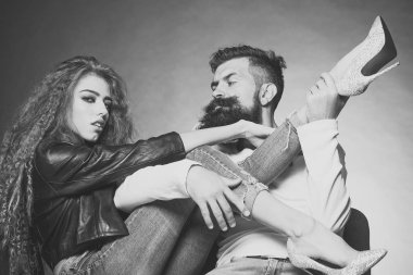 Çift siyah deri ceket kot diamante yüksek topuklu çekerek giyen sandalye genç kadın oturmuş sakallı tıraşsız adam o gri arka plan üzerinde yatay resim gitar gibi kız bacakları oynayan