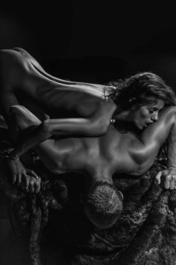 seksi çift uzun saçlı yakışıklı kaslı adam üzerinde kürk ceket studio arka plan üzerinde yatan oldukça ince çıplak kadın