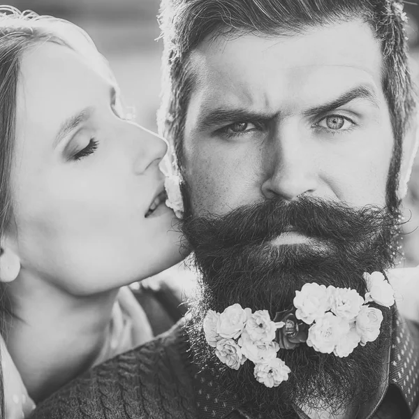 Couple of woman kissing man with long black beard with many little white red and pink flowers sunny day outdoor on natural background.