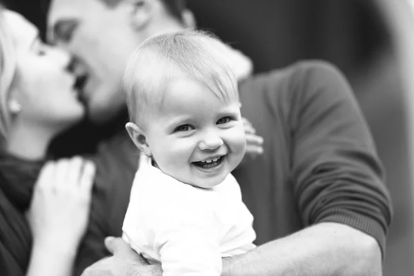 Menino sorri enquanto os pais se beijam — Fotografia de Stock