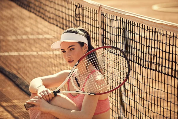 Woman tennis player wearing cap having rest