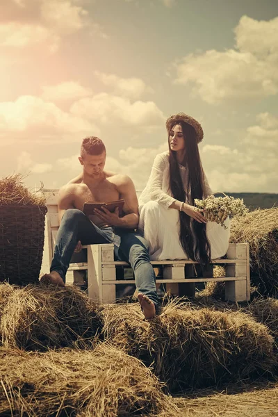 Couple in love sit on bench on hay