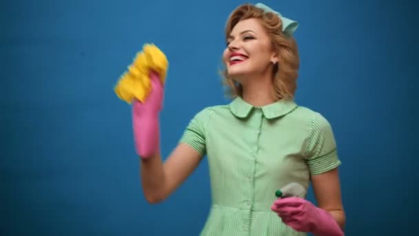 Pin de la mujer en guantes sonriendo y limpiando el polvo con un aerosol y un plumero. Concepto de limpieza con suministros. Hermosa joven mujer hace limpieza. Pin de limpieza. Hermosa mujer en guantes de limpieza . — Vídeo de stock