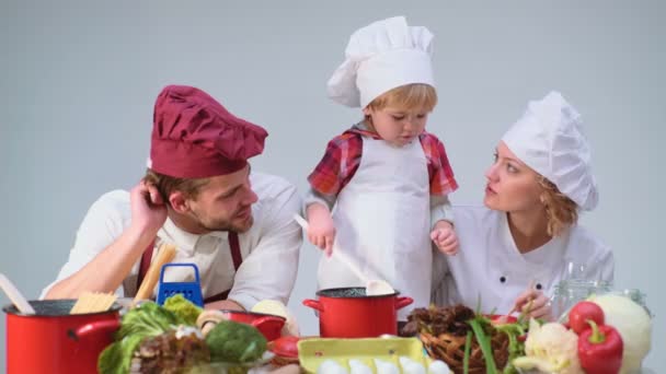 調理キッチン食品の fogetherness コンセプトが家族。一緒にキッチンで食事を調理している家族。かわいい男の子と野菜を切り、自宅のキッチンで料理をしながら笑みを浮かべて彼のハンサムなお父さん. — ストック動画