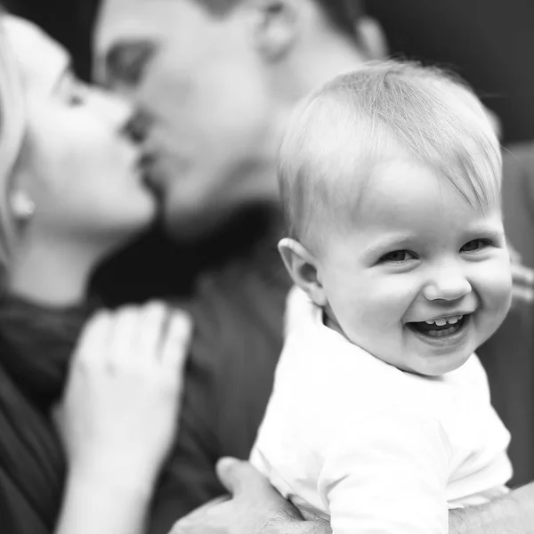Menino sorri enquanto os pais se beijam — Fotografia de Stock