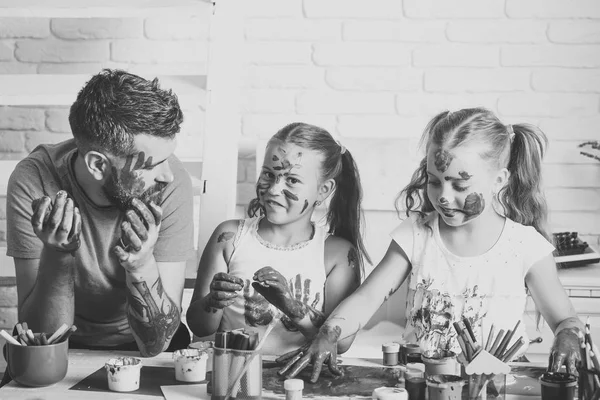 Dad and daughters drawing with colorful paints