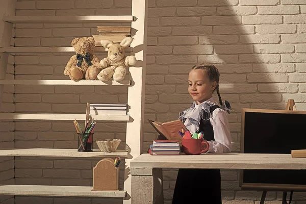 Dziewczyna siedzi przy biurku z kolorowe papeterii i książek — Zdjęcie stockowe