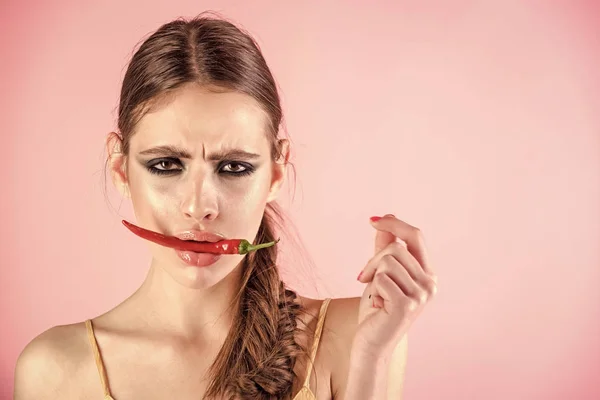 Mujer mantenga el pimiento rojo en la boca sobre fondo rosa —  Fotos de Stock