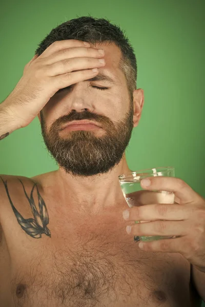 Головная боль человека с бородой на лице пить воду из стекла — стоковое фото