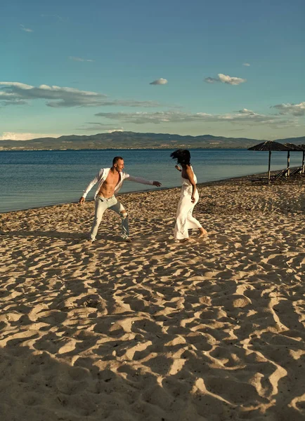 男と女が踊り、バカンス幸せなカップル。ビーチ、海岸を走る愛のカップル。歩いて、楽しみ、海とのスカイラインの背景を持つ愛のカップル. — ストック写真