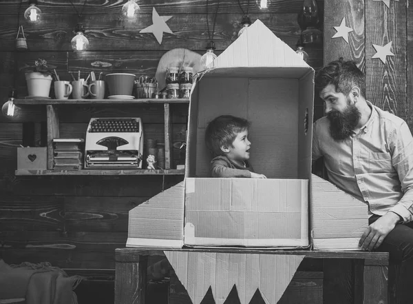 Хлопчик грає з татом, татом, маленький космонавт сидить у ракеті з картонної коробки. Дитина щаслива сидіти в картонній руці, зробленої ракети. Концепція батьківства. Дитячий милий хлопчик грає космонавта, космонавта — стокове фото