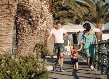Anne ve baba ile oğul plaj palms adlı yürümek. Mutlu bir aile tatil yaz. Sevgi ve güven aile değerleri olarak. Çocuk Anne ve baba ile. Aile Anne ya da babalar gününde çocukla seyahat