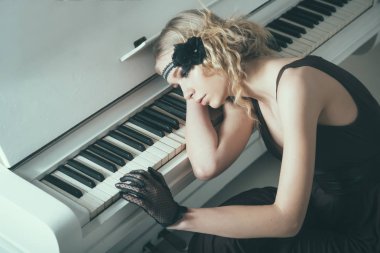 Piyano anılarla bunalmış yatan genç aktris. Klavyede eğilerek üzgün sarışın kız. Kükreyen yirmili kavramı moda.