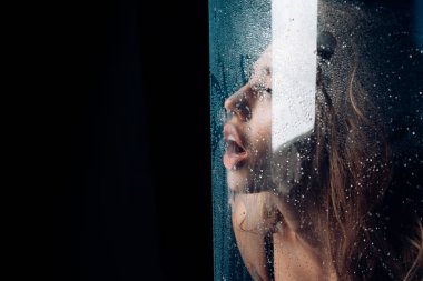 Duş ve hijyen kaplıca tedavisi. Kız makyaj ile daha önce su ile pencere bırakır. Su ile plastik levha arkasındaki seksi kadın bırakır. Moda ve güzellik. Pencere cam kız yüzü ile yağmur damlaları.