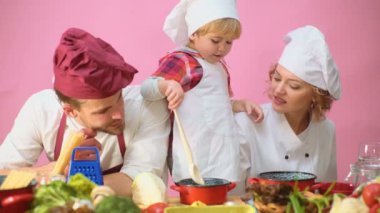 Sevimli küçük bir çocuk ve onun güzel anne mutfakta yemek yaparken gülümsüyorsun. Genç aile yemek yemek mutfakta. Mutlu bir aile birlikte yemek. Mutlu genç ailesi ile anne, baba çocuk yemek.