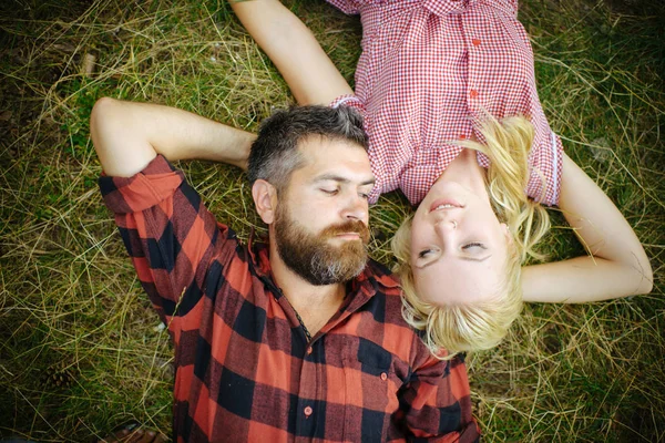 Хіпстер і дівчинка насолоджуються літнім днем на природі. Пара закоханих відпочиває на зеленій траві. Бородатий чоловік і жінка з довгим світлим волоссям. Концепція літніх канікул. Любов романтика і сім'я — стокове фото