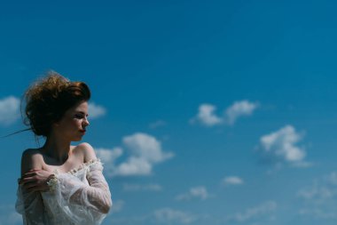 Genç yüz makyaj. Güzellik ve moda vintage tarzı bak. Güzel kız beyaz gelinlik ve retro saç modeli. Moda kadın model poz açık. Yaz aylarında güneşli mavi gökyüzü arka plan üzerinde kız.