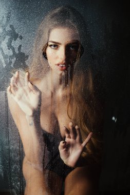 Kız makyaj ile daha önce su ile pencere bırakır. Duş ve hijyen kaplıca tedavisi. Kalp şeklinde pencere camına yağmur damlaları. Moda güzellik ve aşk. Damla su ile plastik levha arkasındaki seksi kadın