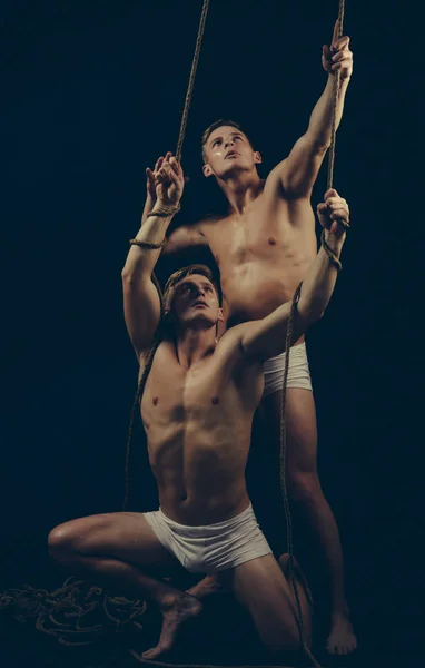 Twee tweelingen mannen doen yoga partners in een sportschool met touw — Stockfoto