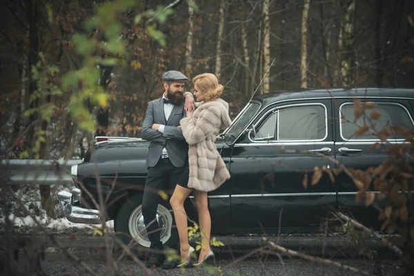 Couple amoureux à un rendez-vous romantique. Rétro voiture de collection et de réparation automobile par le conducteur mécanicien. Voyage et voyage d'affaires ou auto-stop. Homme barbu et femme sexy en manteau de fourrure. Escort de fille par la sécurité . — Photo