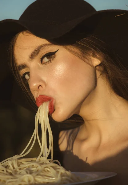 Placa feminina segurando de espaguete em uma mão e comendo com a boca — Fotografia de Stock