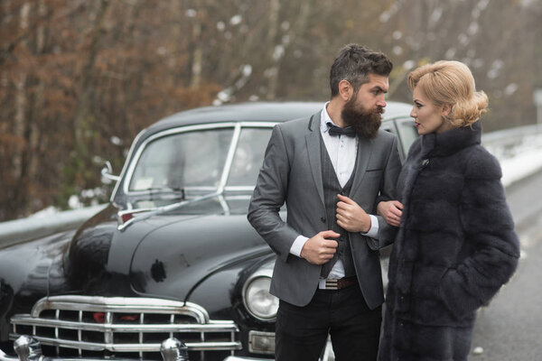 Escort of girl by security. Couple in love on romantic date. Bearded man and sexy woman in fur coat. Retro collection car and auto repair by mechanic driver. Travel and business trip or hitch hiking.