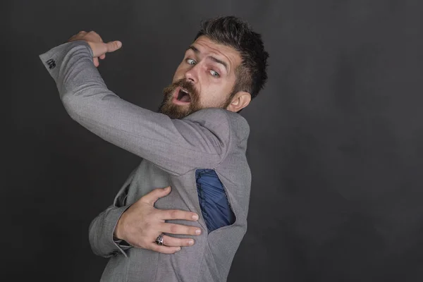 L'uomo barbuto guarda cappotto strappato con sorpresa. Uomo barbuto con barba con foro strappato sulla cucitura — Foto Stock