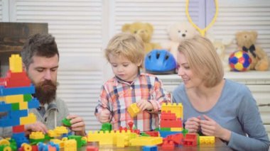Genç aile oyun odası. Aile kavramı seviyorum. Anne, baba ve çocuk oyuncakları ile dışarı plastik blokları inşa. Anne ve oğlu gülümseyen, tuğla yapılar yapmak.