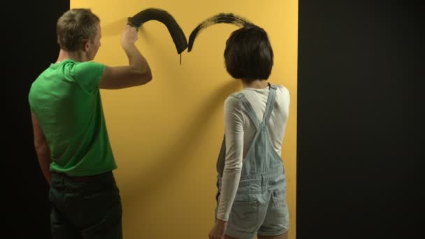 Gelukkige familie tonen verschillende hand tekenen t/m de muur. Lachende en gelukkige familie. Gele muur. Doorbreken van de wand. — Stockvideo