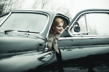 Retro koleksiyonu araba ve otomatik sürücü tarafından onarın. Seyahat ve iş gezisi ya da hiking hitch. Escort ve güvenlik görevlisi lüks kadın için. seksi kadın kürk paltolu. Telekız eski model araba içinde