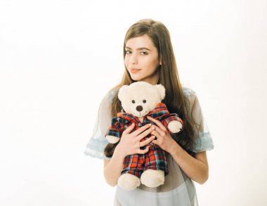 Şeffaf mavi Geceliği Bayan oyuncak ayı eller, beyaz arka plan, kopya alanı tutar. Peluş ayı oyuncak kızla tatlı rüyalar istiyor. Tatlı rüyalar kavramı. Uzun saçlı kadın ihale pijama giyiyor.