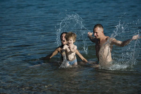 愛と家族の価値観と信頼。息子父と母は、ビーチに海で泳ぐ。家族は、母親や父親の日に子供と一緒に旅行します。父と母と子。幸せな家族の夏休み. — ストック写真