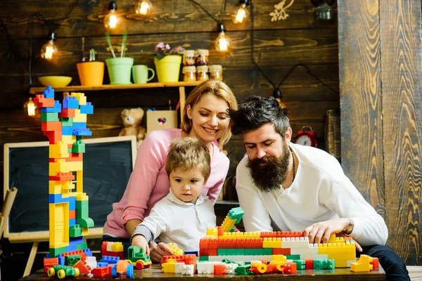 Familia jugando con constructor en casa. Padre ayuda a construir la pared de ladrillos de juguete, bloques de plástico. Madre viendo jugar al hijo con el constructor. Concepto de tiempo familiar . — Foto de Stock