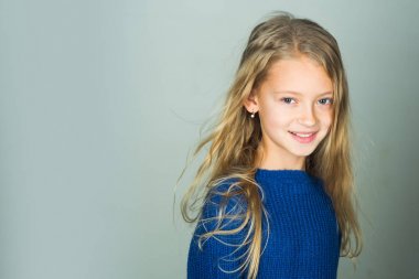 Uzun saçlı küçük kız. Manken, Güzellik, bak. Gri arka plan üzerinde güzel yüzü şık kızla. Kuaför, Cilt Bakımı, rahat tarzı, denim. Güzellik, çocuk moda ve sağlıklı saç.