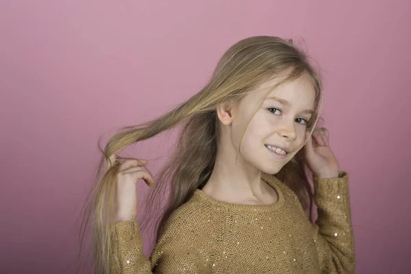 Chica joven bastante alegre con el pelo largo sobre fondo rosa. Preciosos momentos dulces de la pequeña princesa, niño bastante amigable que se divierte a la cámara —  Fotos de Stock