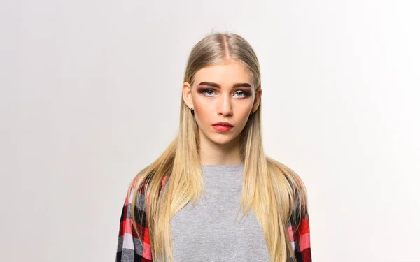 Krásná mladá žena s hodně make-upu, husté obočí a dlouhé blond zářící vlasy při pohledu kamery izolované na bílém pozadí — Stock fotografie