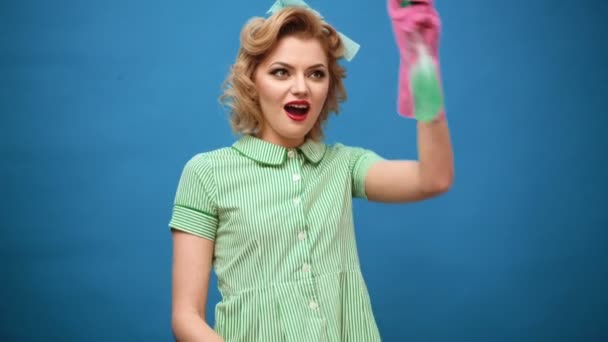 Pin de la mujer en guantes sonriendo y limpiando el polvo con un aerosol y un plumero. Concepto de limpieza con suministros. Hermosa joven mujer hace limpieza. Pin de limpieza. Hermosa mujer en guantes de limpieza . — Vídeo de stock