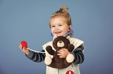 Doktor üniforma içinde mutlu çocuk stetoskop ile oyuncak hayvan incelemek